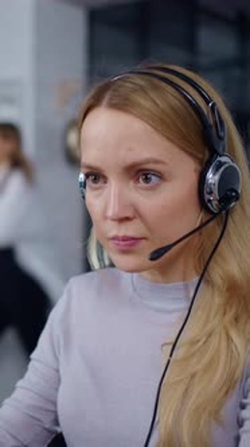 Eine fokussierte Callcenter-Agentin mit Headset kommuniziert mit dem Remote-Client, während sie arbeitet