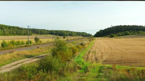 Low altitude aerial drone view moving backwards following on the side of electrified railroad tracks