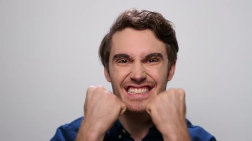 Happy man celebrates victory with yes gesture in studio slow motion on white background