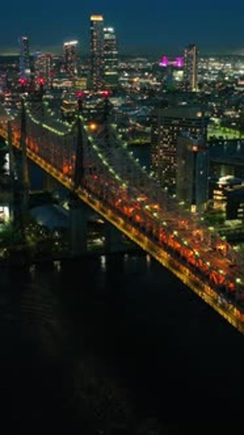 Tremendous multicolored lights of night New York. Bridge crossing the river full of traffic.