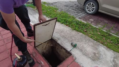 Man Sprays Liquid into Open Sewer Drain