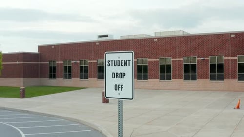 Student Drop Off sign at red brick school building in USA. American education system.