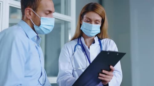 In Hospital Man with Medical Mask Sitting Speaking with Woman Doctor About Diagnosis During