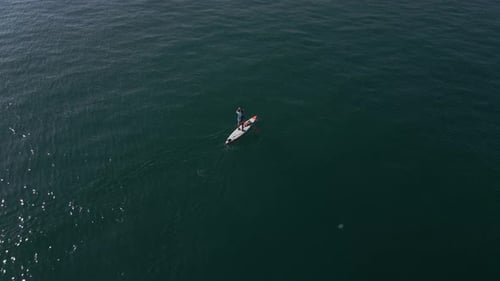 Aerial View of a Man Paddling a Standup Paddleboard or SUP Board on a Calm Sea