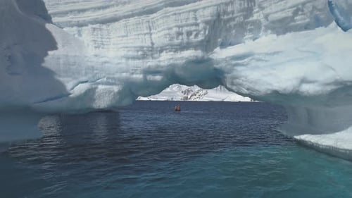 Boat Sails Through Iceberg Archway in Antarctica