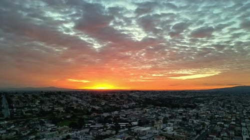Aerial view of city lightened by stunning sunset, urban area merging perfectly with nature