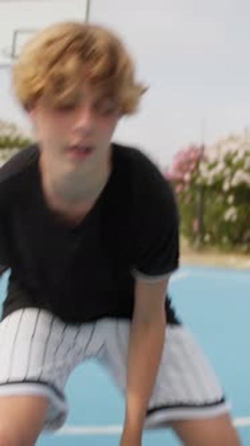 Teenage Boy Dribbling Basketball on Blue Court