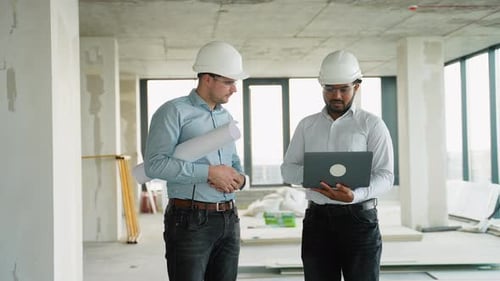 Indian and Caucasian Designers with Laptop are Planning a New Office Renovation