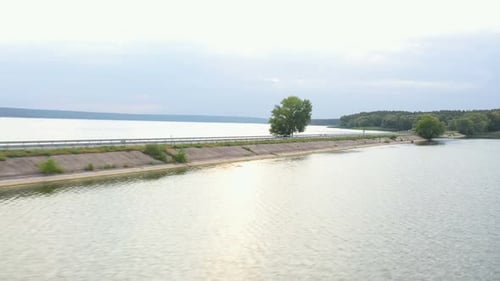 Aerial Shot of Motorcyclist Racing His Motorcycle Through Road Near Lake Man Drive Bike at Dam Route