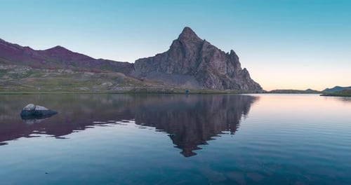 Anayet peak and blue tent near lake reflection in Pyrenees mountains during sunrise in Aragon, Spain