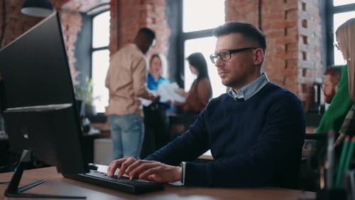 Modern Businesspeople Working In Office Portrait Of Man At Computer Against Colleagues