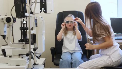 Looking forward. Little girl at the ophthalmologist clinic with doctor.