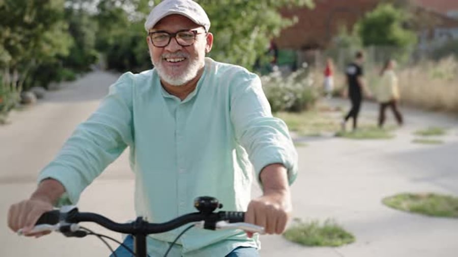 Cover for Cheerful Hispanic Senior Man Having Fun Riding Bicycle at City Park Healthy Lifestyle