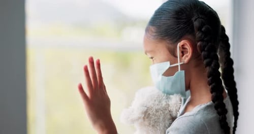 Sad, girl with face mask and at window in living room of her home for compliance