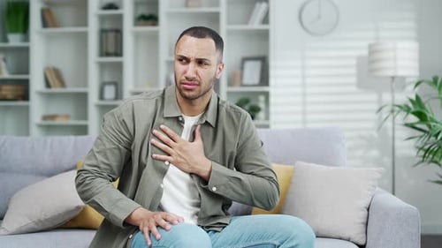 Young Man Experiencing Chest Pain On Sofa