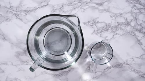 Glass Measuring Cups with Water on Marble Surface