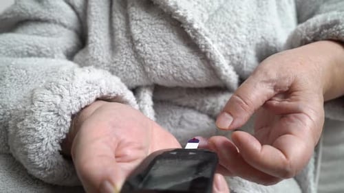 Diabetic Patient Measuring Blood Glucose Level with a Glucometer