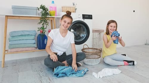 Happy Sisters Throwing Laundry Clothes at Camera