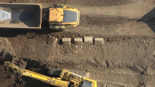 Excavator Loading Yellow Truck on Construction Site