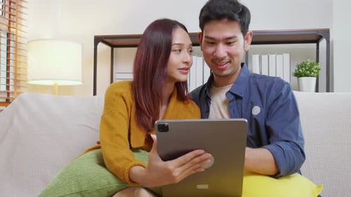 Couple Uses Tablet Together on White Sofa