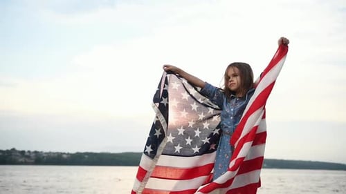 Girl Holds an American Flag Near a Lake