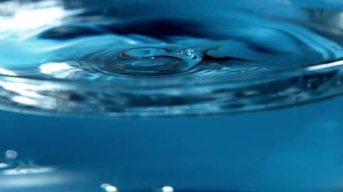 Water Droplets Forming Ripples on Blue Surface