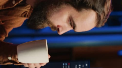 Man Drinks Coffee While Working Late on Computer