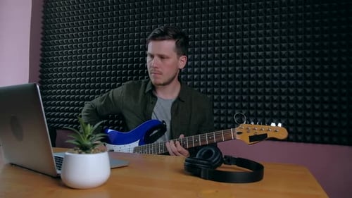 Young Adult Plays Guitar at Music Workplace