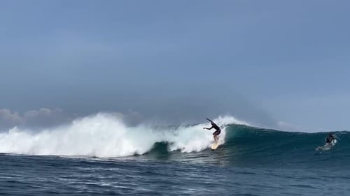 Joven surfista monta una ola azul