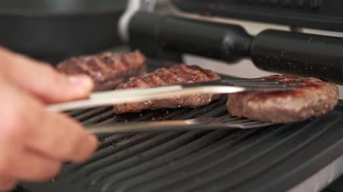 Modern Electric Grill Closeup of Beef Steak Chop Cooking on Barbecue Metal Grill at Home Kitchen