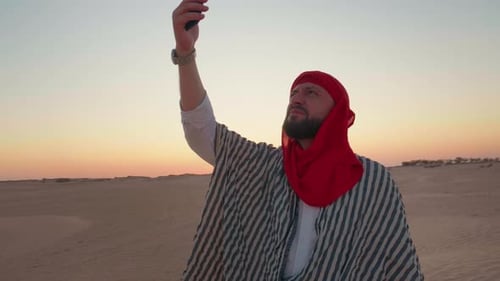 Man trying to search signal with cellphone walking on desert.