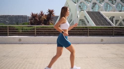 Young Woman Runs in Urban Setting on Sunny Day