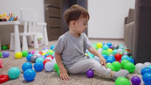 Young Boy Plays with Colorful Balls at Home
