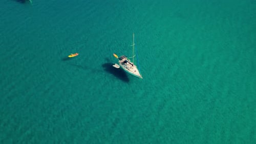 Small boats yachts and sailboat anchored and Stand up Paddles SUP floating through the turquoise