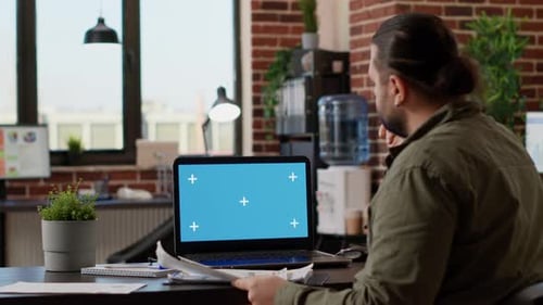 Office Worker Looking at Greenscreen Template on Laptop