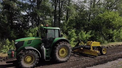 Grader arbeitet mit Traktor und ebnet die Feldstraße