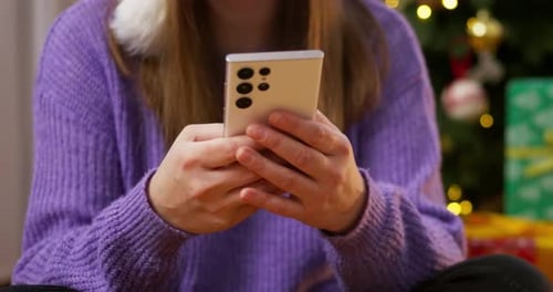 Woman Using Smartphone Near Christmas Tree