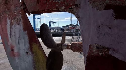 The rusty engine and rudder propeller of the old fishing boat in the shipyard for restoration with t