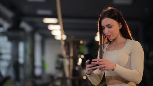 A Woman is Using a Cell Phone in a Gym