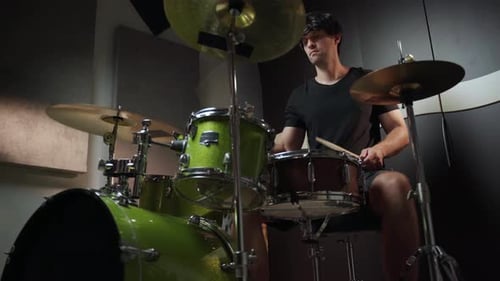 Man Playing Green Drum Kit in Music Studio