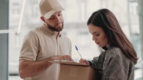 Young Woman Signing Delivery Form From Courier with Package