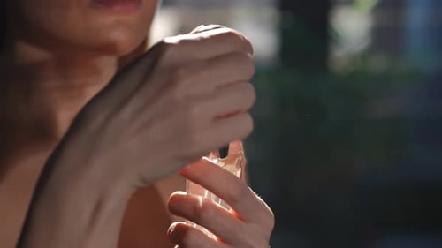 Woman Sprays and Smells Perfume in Sunlight