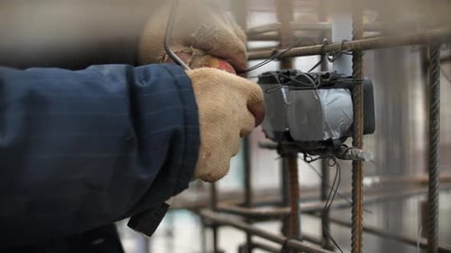Trabajador asegurando la caja eléctrica a la estructura de barras de refuerzo