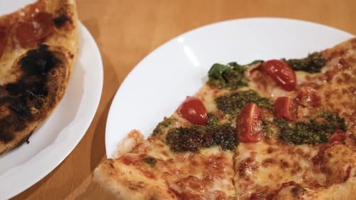 close up shot of delicious Italian pizza slices in white plates on the wooden table at home, sliding