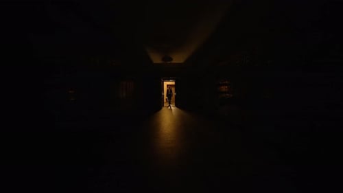 Silhouetted Man Walking in Dark Hallway at Night