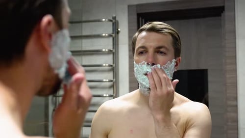 Man Applies Shaving Cream in Modern Bathroom