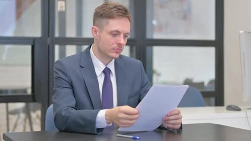 Man in Suit Reviews Documents in Office