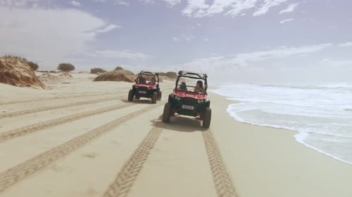 Two ATV Vehicles Racing on a Beautiful Beach with Ocean and Open