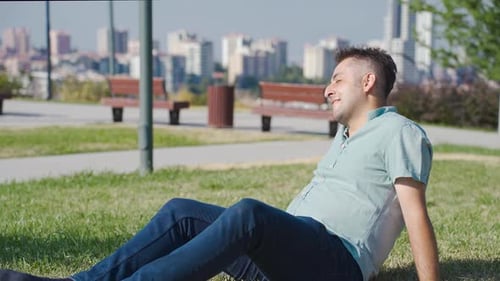 Young Adult Relaxing in City Park on Lawn