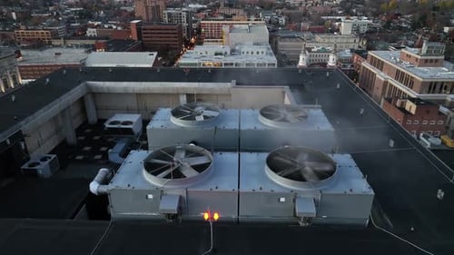 Aerial orbit shot of rotating propeller of Air Conditioner on top of tower in Lancaster City at suns